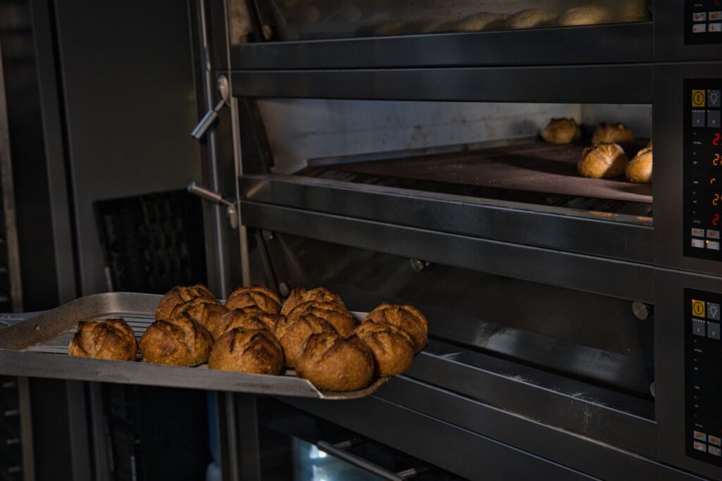 Fournée de pains sortant d'un four électrique professionnel à étages dans une boulangerie artisanale